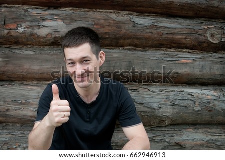 Handsome man makes thumb up, good sign. Rustic style, village