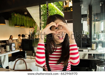 Beautiful young asian woman smile and make hand like a heart from love in the cafe , happy girl , smile time , hipster girl