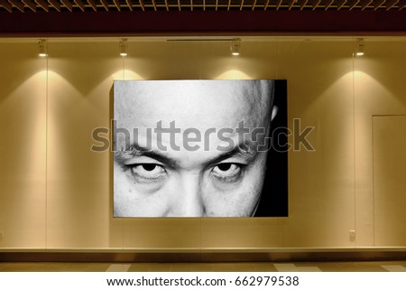 A mysterious man staring from a picture frame illuminated by downlight in a showcase.