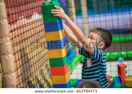 Little boy playing plastic block indoor playground activity