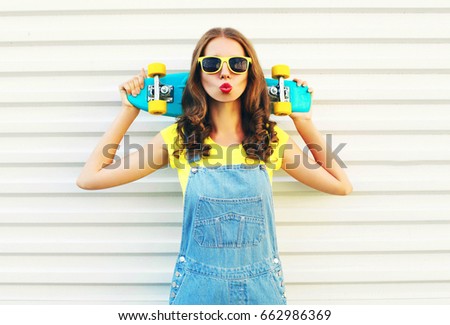 Fashion cool girl blowing her lips with a skateboard over a white background