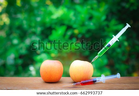 Needle and syringe injected in the apple, Enhanced fruits. Nutrition concept, GMO concept. Background of nature. Dark tone
