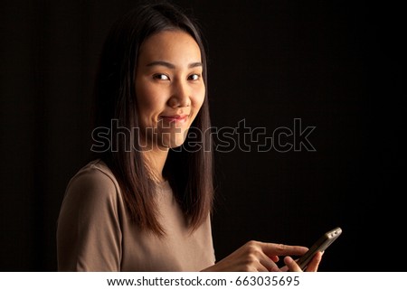 young beautiful asian woman with mobile phone isolated on black background