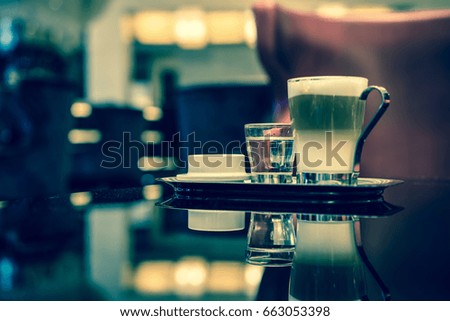 Glass of latte Coffee cup and syrup on the table in lounge bar background.