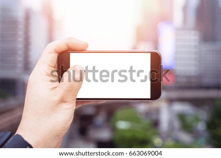 Man uses his Mobile Phone at cityscape background in morning light, close up, capture the moment by a smart phone in my hands. cityscape background. building background. white screen.