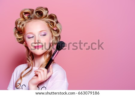 Portrait of a pretty girl teenager with curlers in her blonde hair and brushes. Teen style, fashionable teen girl. Cosmetics and make-up.