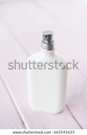 Parfume white bottle on light pink wooden backdrop