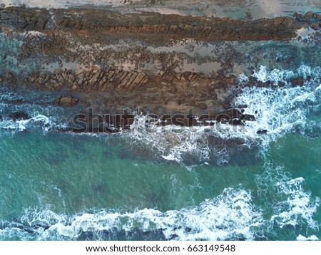 Beach with stones top view. Green ocean water in pacific above view