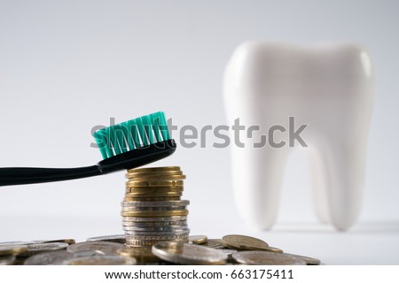 Dentures, denture and oral hygiene. Tooth brush on heap of stacked coins isolated on a white background. Dentist Money concept. Healthcare reform concept. Medical insurance medicare reimbursement.