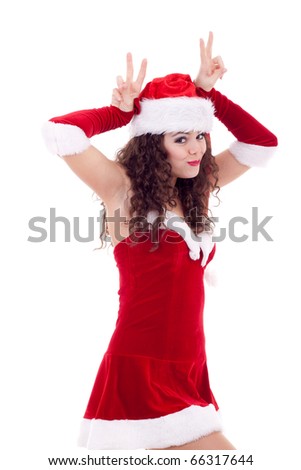 Picture of pretty christmas girl in red dress and santa hat, making horns with her fingers, smiling isolated on white background