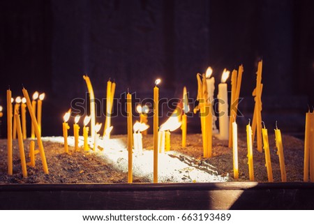 Candles in Armenian traditional Christian Apostolic Church in the darkness. Five yellow candles burned with black background.