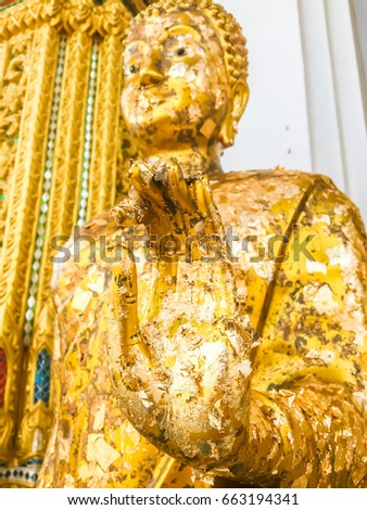 Close up hand and head filled with gold leaf of statue Buddha. concept shows the devotion of the Buddhists.