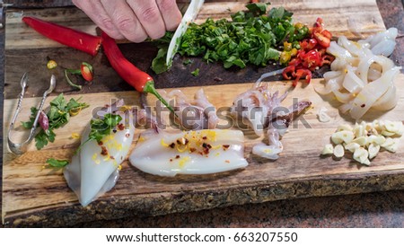 preparing ingredients for black pasta with squids (cuttlefish) and ink: cutting parsley Royalty-Free Stock Photo #663207550