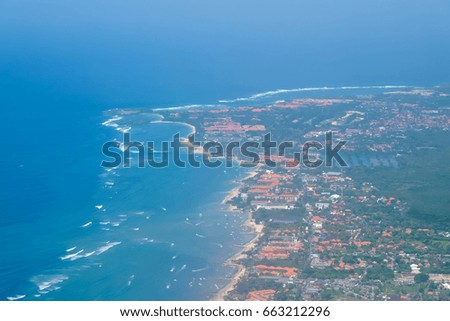 Scenery from airplane 's window seeing sea water , white clouds , blue sky and Bali islands