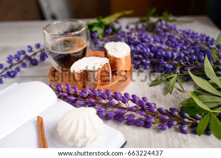 Note with a pen, a calendar and a Cup of coffee served with bruschetta, lupins flowers on wooden table