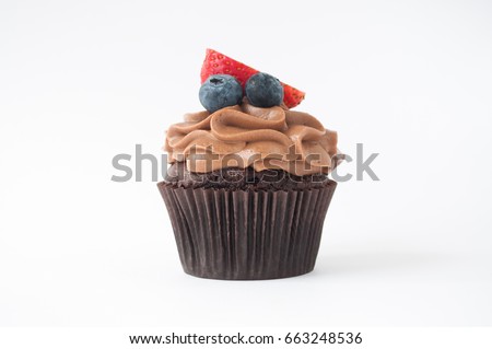 Chocolate cupcake with whipped chocolate cream, decorated fresh strawberry, blueberry on white background. Picture for a menu or a confectionery catalog.