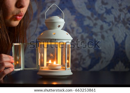 girl blow out a candle in a lantern