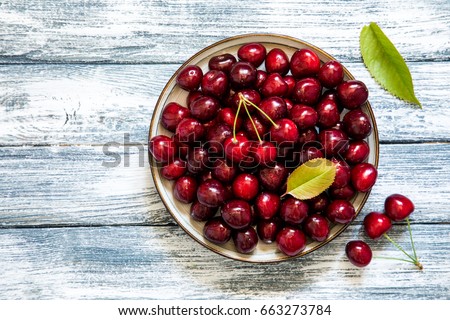 Fresh cherry on plate on wooden blue background. fresh ripe cherries. sweet cherries. Royalty-Free Stock Photo #663273784