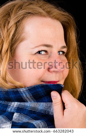 Portrait of a attractive european light overweighted red haired female with blue lumberjack shirt - view on head, studio shot in fron of black background