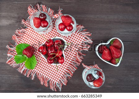 Cherries and strawberries in bowls in the form of hearts, Berries of blueberries and strawberries are scattered on the table. Cooking, healthy food, food packaging