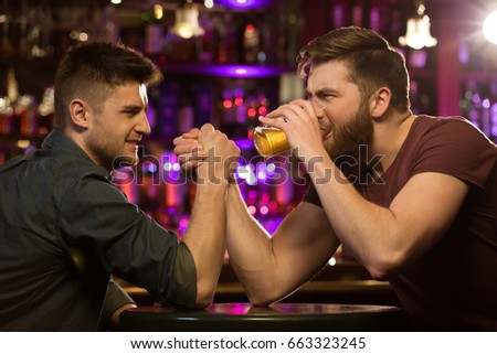 Two friends drinking beer and having fun at the pub or bar