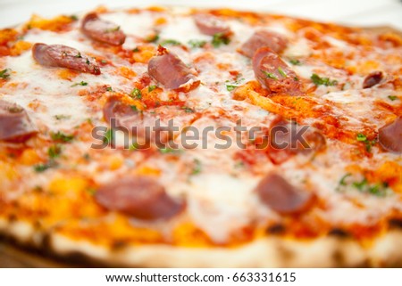 tasty hot pizza with cheese and beef sausages on white wooden table
