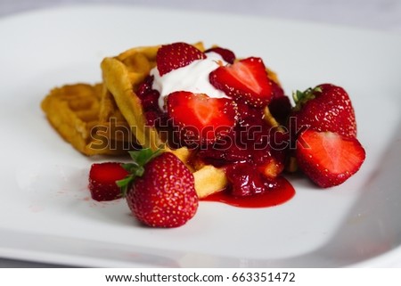 Waffles with strawberries, homemade berry sauce and cream