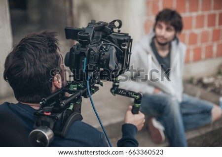 Behind the scene. Actor in front of the camera on the film set outdoor location. Group movie scene Royalty-Free Stock Photo #663360523
