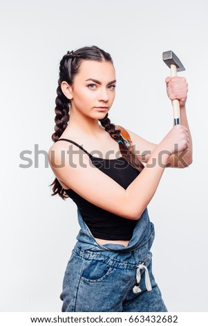
Dark-haired young beautiful girl is confident, holding a hammer with both hands, Isolated on white background, repair