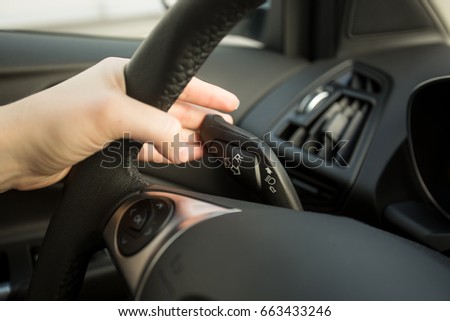 Woman driving car and using turn signal switch Royalty-Free Stock Photo #663433246