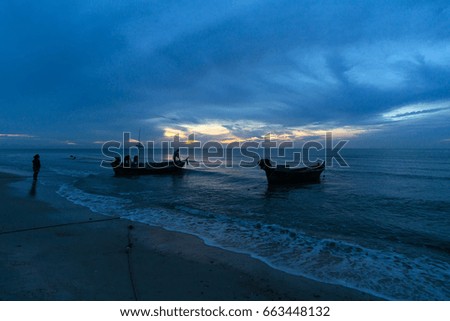 Fishing boats with fishermen in the sea before sunrise.