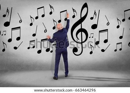 View of a Businessman in front of a wall writing music notes - Art concept