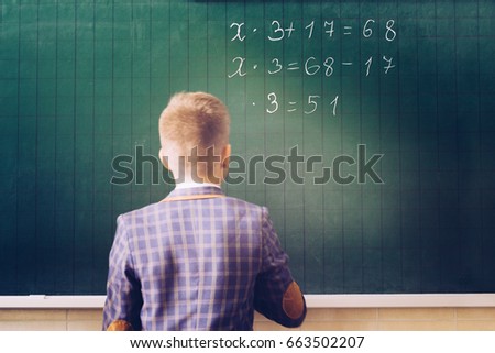 Green chalkboard with equation. Child writing on green chalkboard with withe chalk