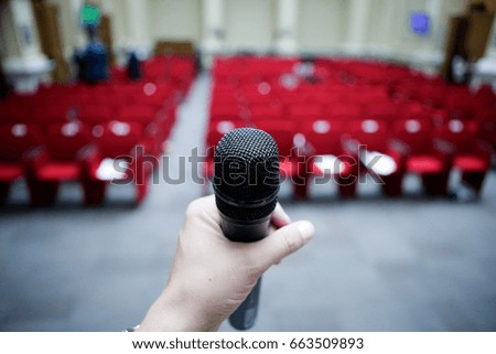 Man holding a microphone in front of an empty hall