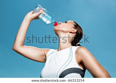 A tanned sports woman thirsty and drinking in summer Royalty-Free Stock Photo #66353254