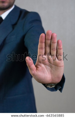Young businessman man in jacket and white shirt shows gesture stop sign. Business concept, focus on hand