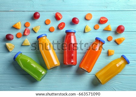 Different juices in bottles with ingredients on wooden table