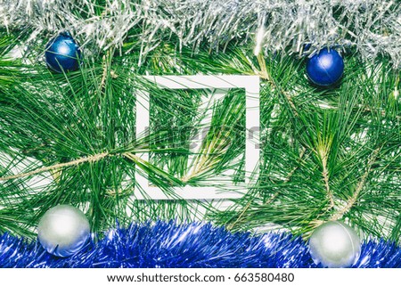 X-mas background with blue and silver decoration, christmas balls on green pine leaves. Empty square copy space for text