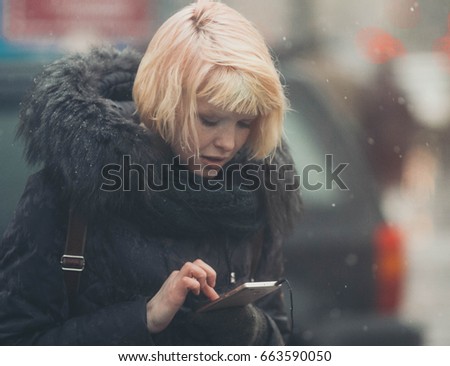 Winter beautiful woman city portrait using mobile. Outdoor shot.