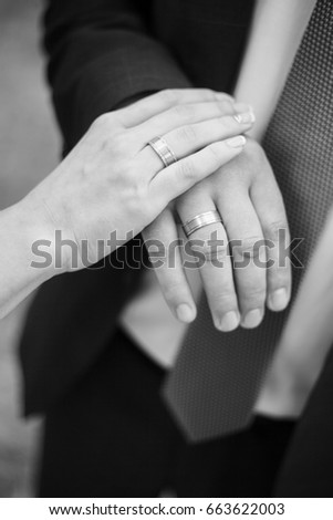 Details of the wedding day. Wedding photo session in the forest on a sunny day. Hands and rings of the bride and groom. Black and white picture