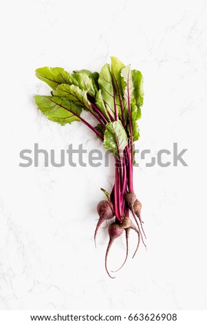 Young beets with leaves on a white marble surface view from the top vertical, red and green colors, healthy ingredient