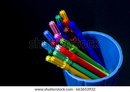 Color marker pencils blue globes black background isolated 
