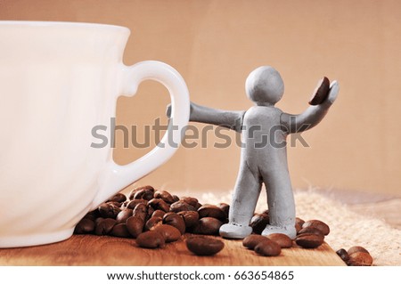 Gray plasticine man holding coffee bean with a white cup and more coffee beans on the wooden cutting board