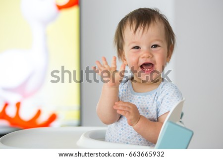 Baby boy waving his hand while watching cartoons (11-month-old).