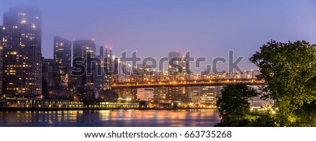 Midtown Manhattan New York City skyscrapers and 59 street bridge illuminated in evening.