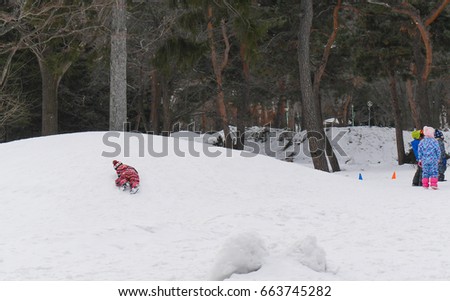 child on snow behind his friends