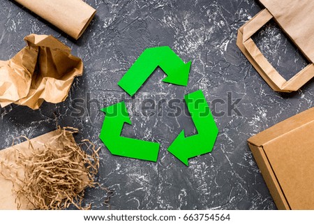 Paper recycle sign with paper and carton garbage on grey table background top view