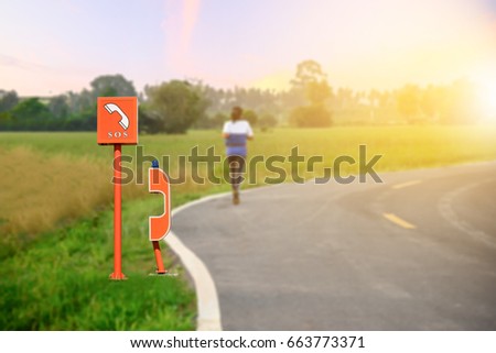 SOS Service point on road, SOS Emergency phone installed on side of the road and woman jogging background with sunset
