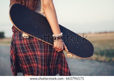 Close up of a teenage girl holding skateboard