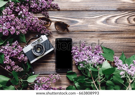 planning travel and wanderlust flat lay with empty phone screen sunglasses camera and lilac flowers on wooden rustic background top view. spring picture with space for text.  summer vacation